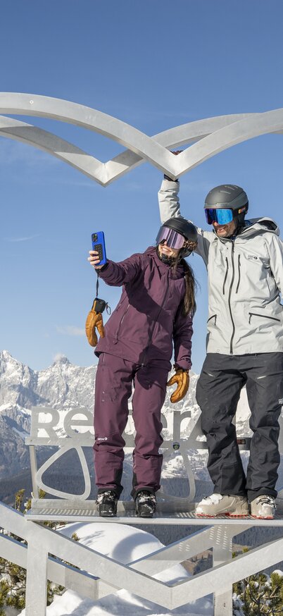 2 SKifahrer stehen im Steirerherz auf der Reiteralm drinnen und machen ein Selfie. | © Lorenz Masser
