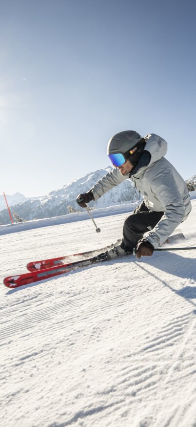 Skifahrer fährt bei Sonnenschein die Piste der Reiteralm hinunter. | © Lorenz Masser