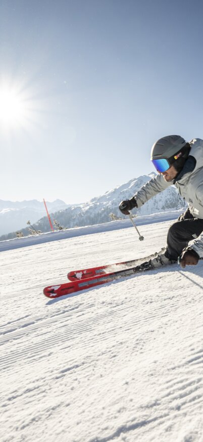 Skifahrer fährt bei Sonnenschein die Piste der Reiteralm hinunter. | © Lorenz Masser